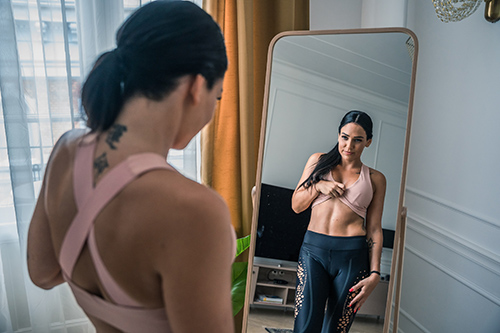 Woman lifting her shirt and looking at her stomach in the mirror and liking what she sees