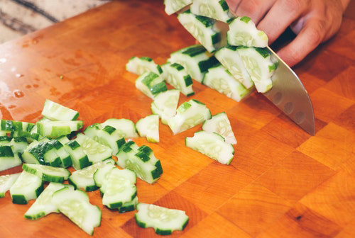 cucumbers being cut into little bite size chunks with a knife
