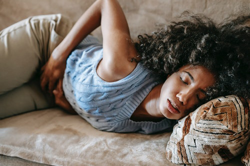woman curled in pain on the couch because of gastritis