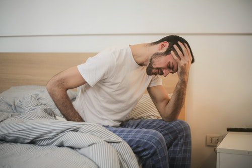 Guy with stomach pain sitting at the edge of his bed