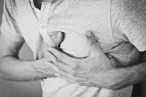 man holding his chest in pain due to angina