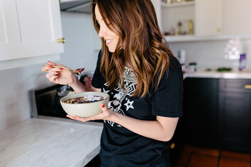 Woman eating a bowl of lentils and brown rice in her kitchen
