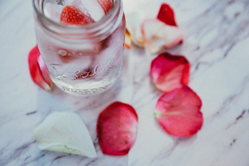 rose petals on table next to glass jar