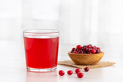 glass of cranberry juice with cranberries in a wooden bowl