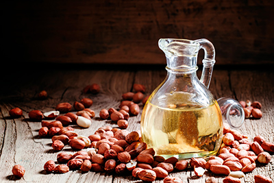 bottle of peanut oil with shelled peanuts surrounding it on a table