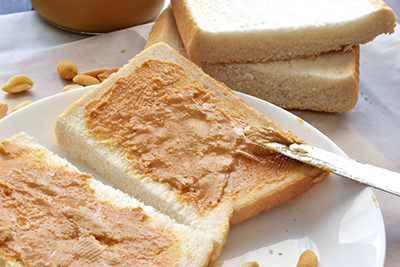 peanut butter being spread on two slices of bread