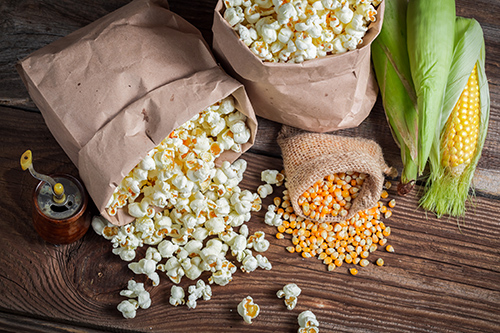 two bags of popcorn next to 3 corn cobs