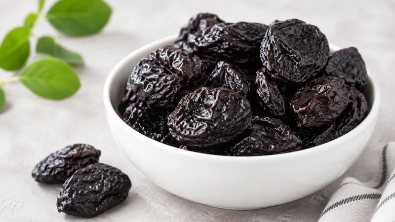 A white bowl of dried prunes, the most clinically studied food for constipation relief