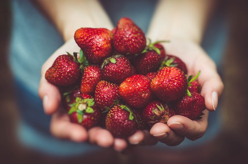Angina pectoris foods to avoid: Image of person holding a bunch of strawberries in their hands.