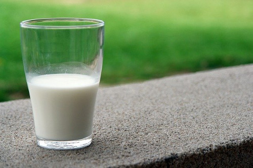 Foods to avoid with eczema: Image of a glass of milk half full.