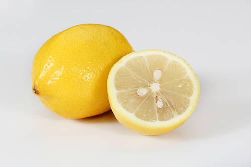 Foods to eat when you have a fever: Image of a full and half cut lemon.