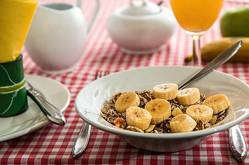 how to increase fiber intake: Image of a plate of cereal topped off with bananas