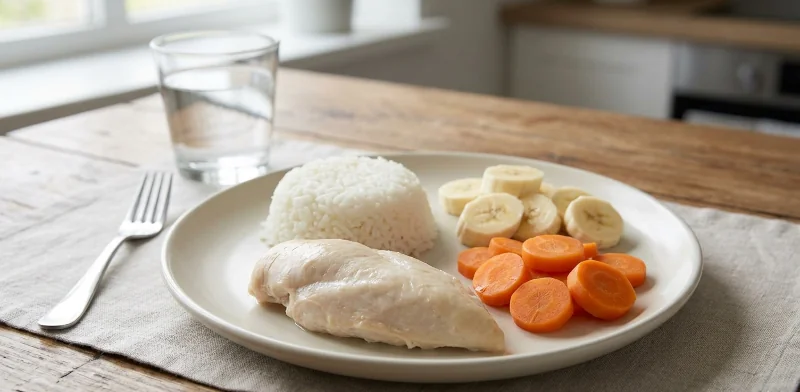 Low-residue plate with white rice, baked chicken, peeled cooked carrots, and banana for ulcerative colitis flare.