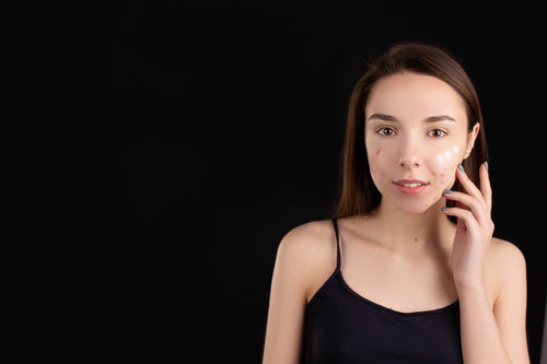 woman puting cream on her face because of eczema