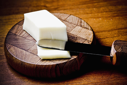 lard on a wooden bowl with the knife that sliced a sliver