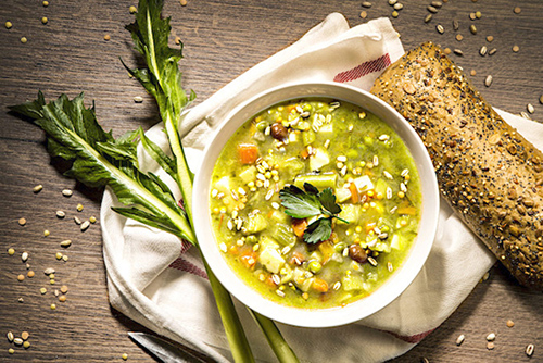 Nutritious soup in a bowl alongside roll of bread