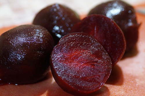 red beets with one sliced in half showing how juicy it is