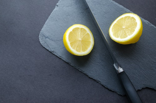 lemon cut in half on the table with the knife inbetween the two halves