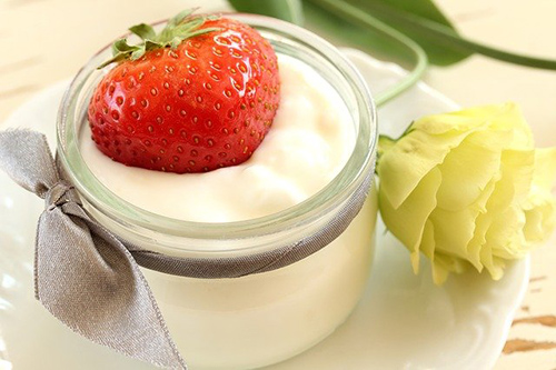 A cup of yogurt with a strawberry inside