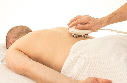 man laying on his stomach and appears to be getting some form of kidney massage