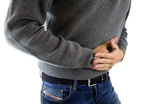 man holding his stomach with both hands due to flatulence and bloating
