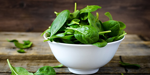 filled bowl of spinach on a table