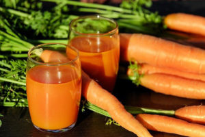 two glasses of carrot juice surrounded by carrots