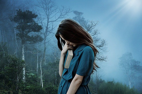 teenage girl holding book with head down suffering from anxiety and depression