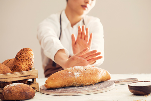 digestive problems with bread: woman pushing away a loaf of bread