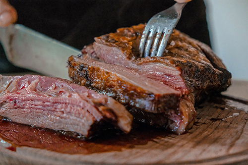 fork and knife cutting into delicious steak.