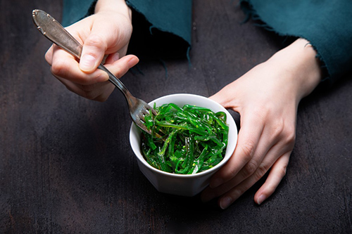 image of hands with a fork inside a bowl of bladder fucus seaweed