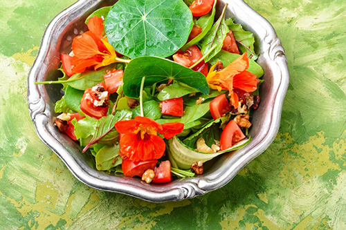 nasturtium salad with nuts and other vegetables in a bowl