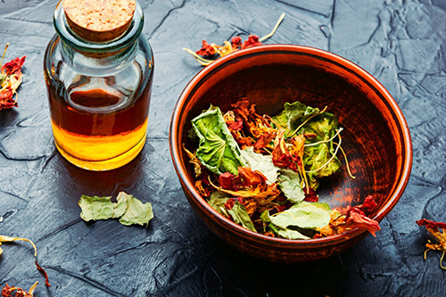 nasturtium leaves dried in bowl on table with essential oil in a bottle