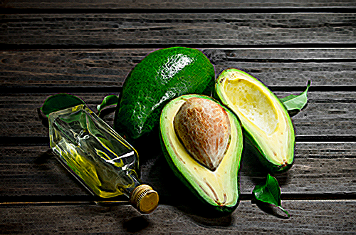 avocados next to a bottle of avocado oil