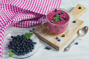 bilberries in a bowl and bilberry smoothie in a glass