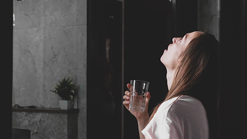 woman holding glass gargling decoction made with blessed herb