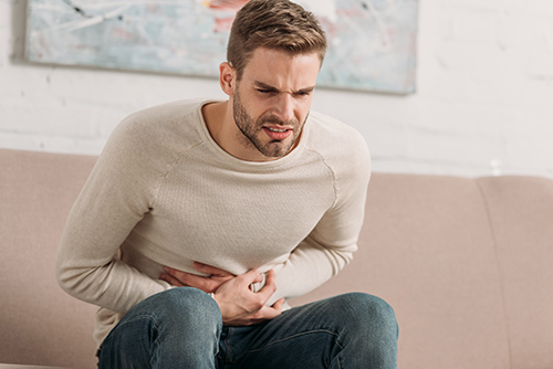 man crouching over with stomach pain