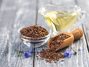 Flaxseeds in a bowl next to a jar with flaxseed oil