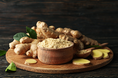 ginger health benefits with ginger root and powder on a wooden board