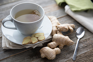 ginger tea in a teacup with slices of ginger root on a saucer