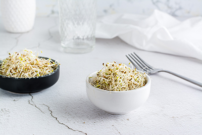 two bowls on a table filled with alfalfa sprouts