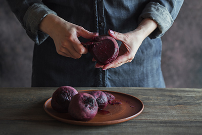 man peeling red beets on a table