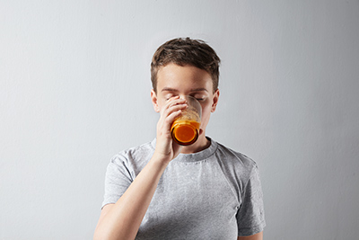 boy drinking a glass of carrot juice