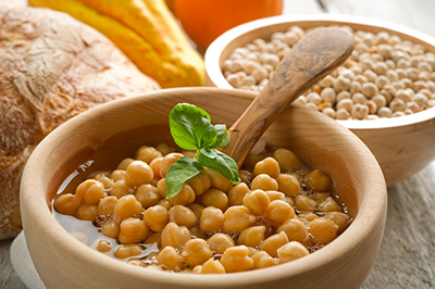 chickpea soup in a wooden bowl and wooden spoon.