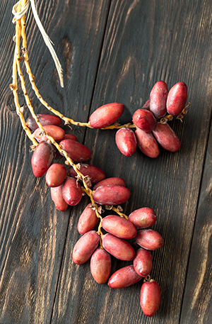 cluster of dates attached to branch on a wooden background