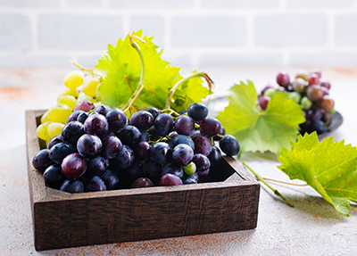 wooden container filled with black and green grapes