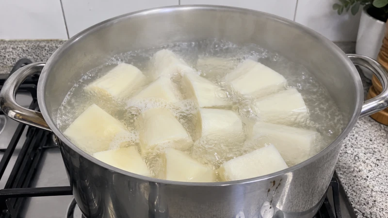 Peeled yam pieces being boiled in a pot, showing the cooking step needed before eating.