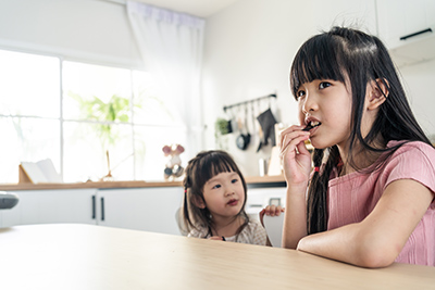 two little girls sitting at a kitchen table