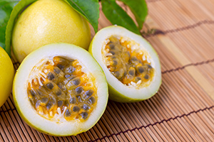 yellow passion fruit sliced open with whole one in the background