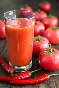 glass of tomato juice with tomatoes in the background